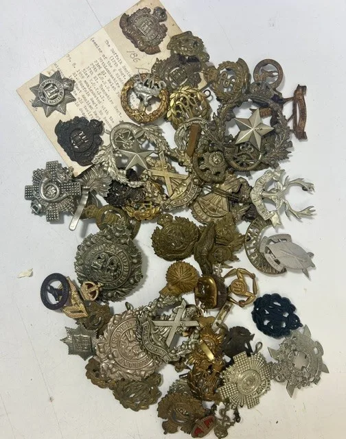 A large collection of early 20th century cap badges, collar badges and shoulder titles to include Union Defense South Africa, Suffolk, Devonshire regiment