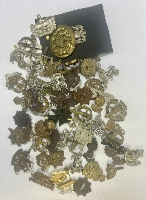 A large collection of early 20th century cap badges, collar badges and shoulder titles to include West Kent Regiment, King's Own, Educational Corps