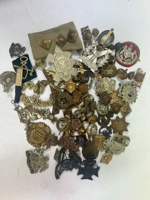 A large collection of early 20th century cap badges, collar badges and shoulder titles to include South African Royal Artillery