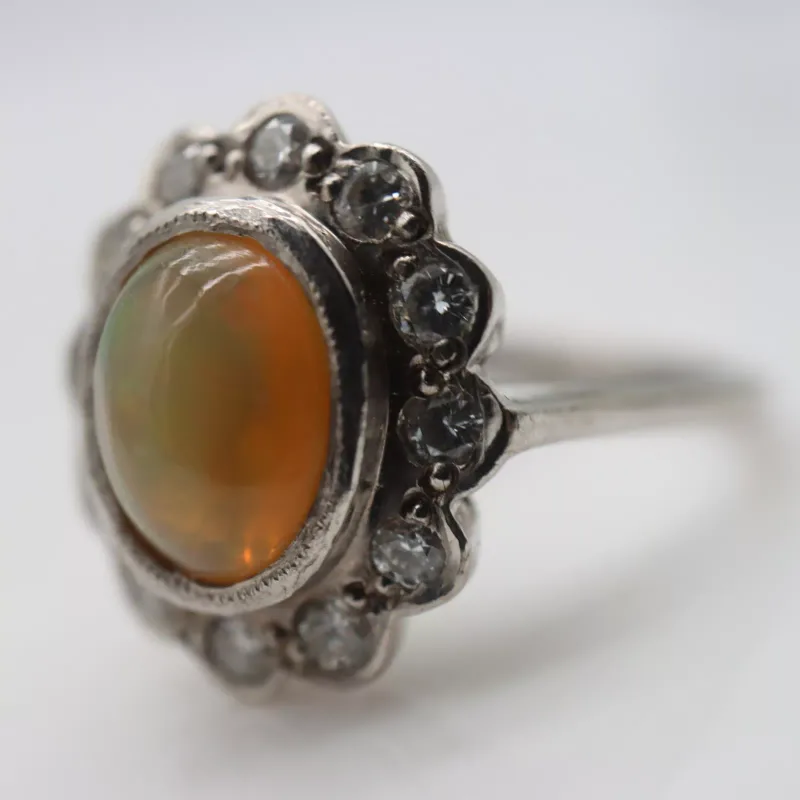 18ct white gold ring set with a central opal cabochon and surrounding diamonds, size N, 6.6g, opal W: 10 mm, each diamond D: 2 mm