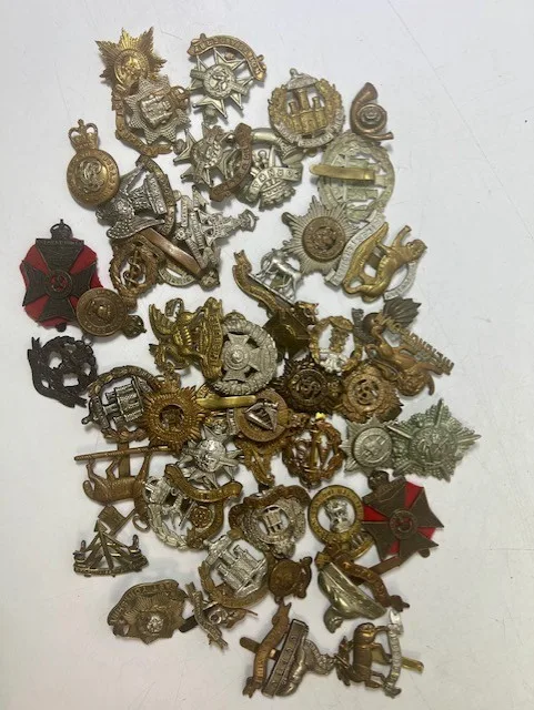 A large collection of early 20th century cap badges, collar badges and shoulder titles to include Leicestershire, Dorsetshire, Lincolnshire, Suffolk