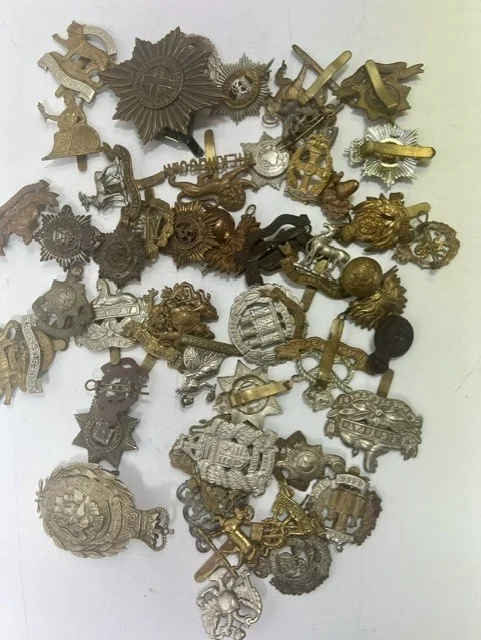 A large collection of early 20th century cap badges, collar badges and shoulder titles to include Gloucestershire, Northamptonshire