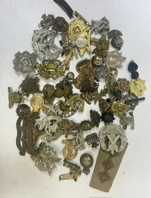 A large collection of early 20th century cap badges, collar badges and shoulder titles to include Machine Gun Corps, King's Own, Gloucestershire