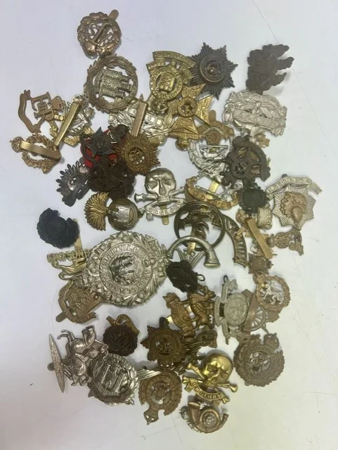 A large collection of early 20th century cap badges, collar badges and shoulder titles to include Argyll & Sutherland, Parachute regiment