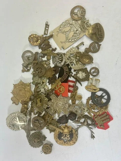 A large collection of early 20th century cap badges, collar badges and shoulder titles to include Gordon Highlanders, Royal Marines, Welsh regiment
