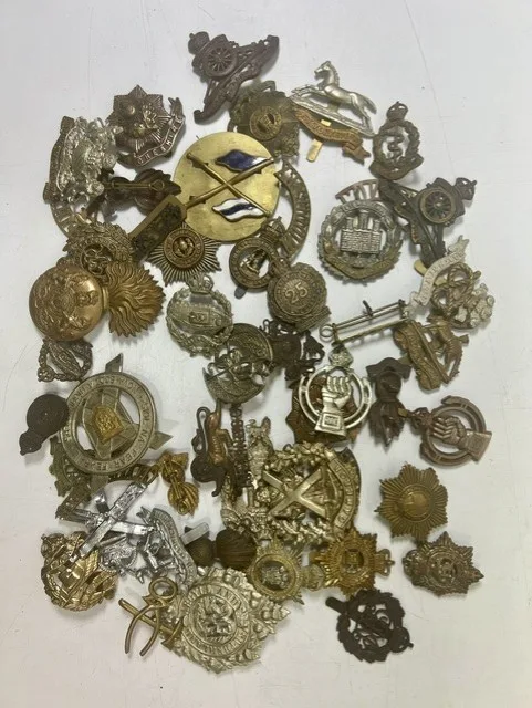 A large collection of early 20th century cap badges, collar badges and shoulder titles to include Tank Regiment, Manchester, East Yorkshire, King's Own