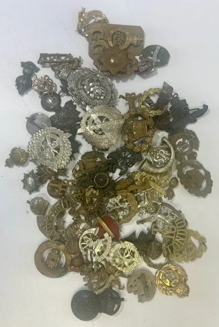 A large collection of early 20th century cap badges, collar badges and shoulder titles to include Small arms corps, Somerset Light Infantry
